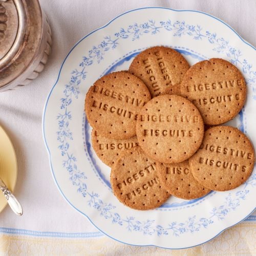 A plate of plain biscuits on a table with the words 'digestive biscuits' pressed into the surface.