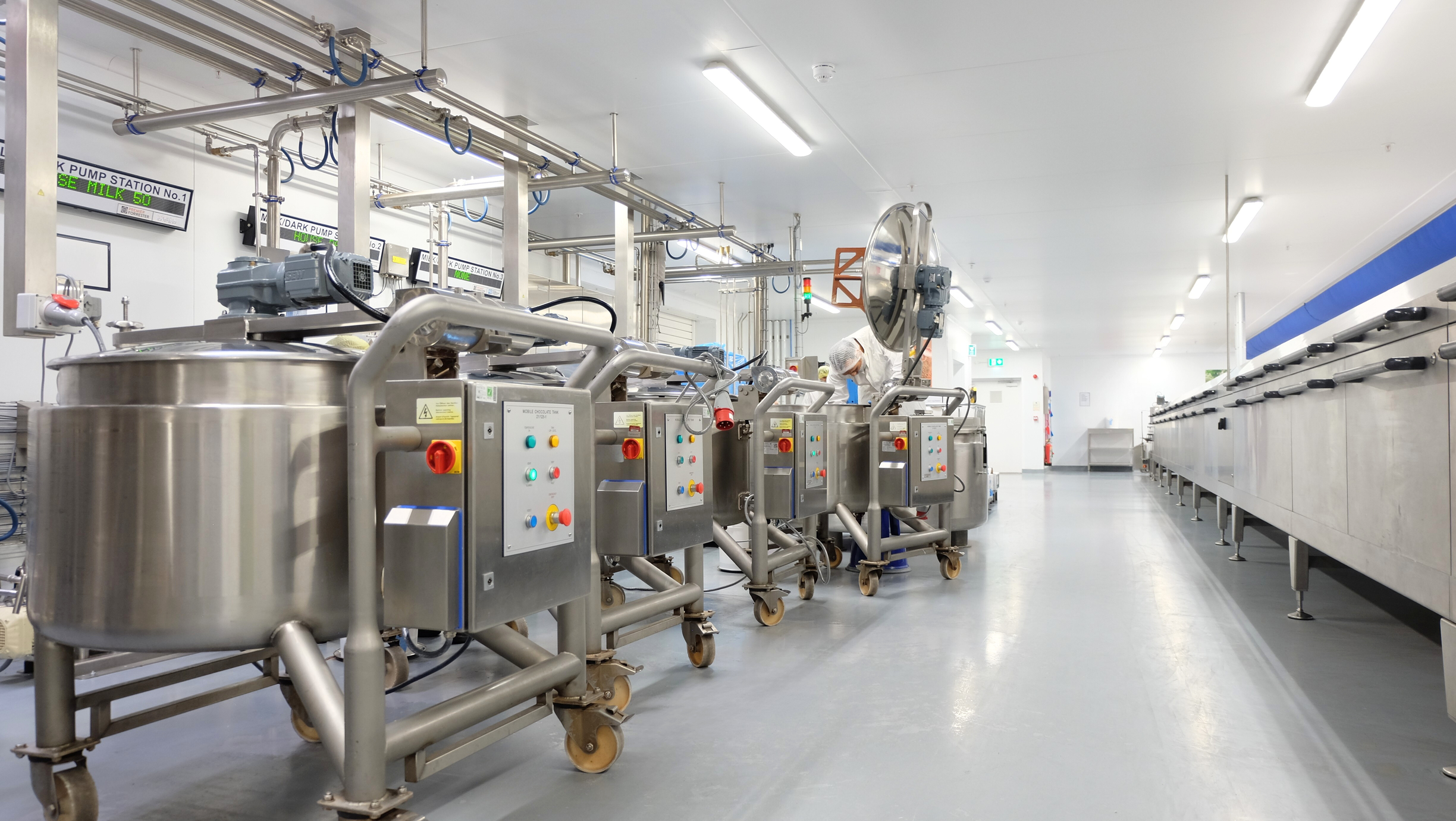 Four mobile chocolate tanks on wheels in a production environment. 