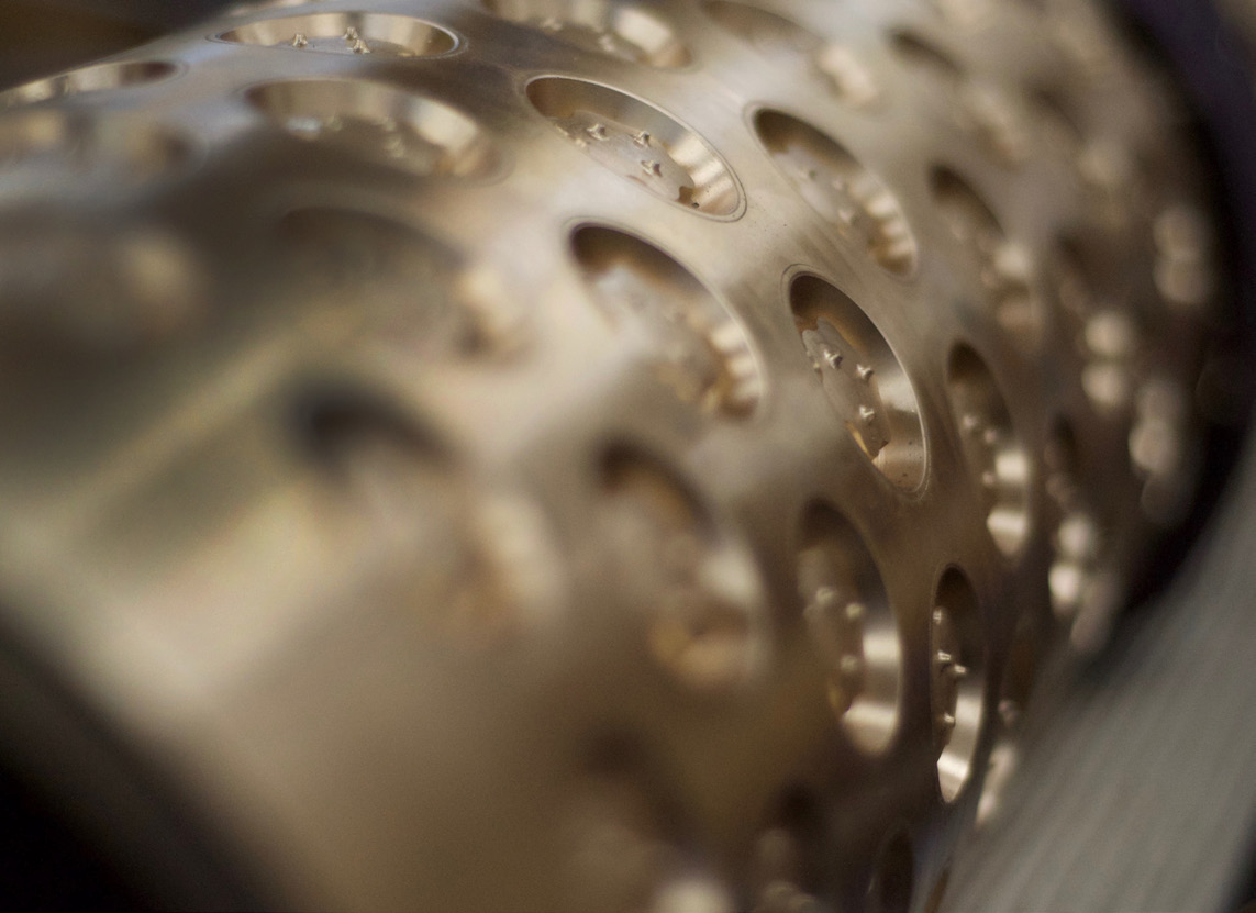 Close-up of a brass rotary moulder used in industrial dough forming.