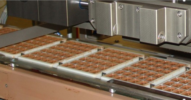 Industrial chocolate depositing machine filling mould trays with precision and consistency.