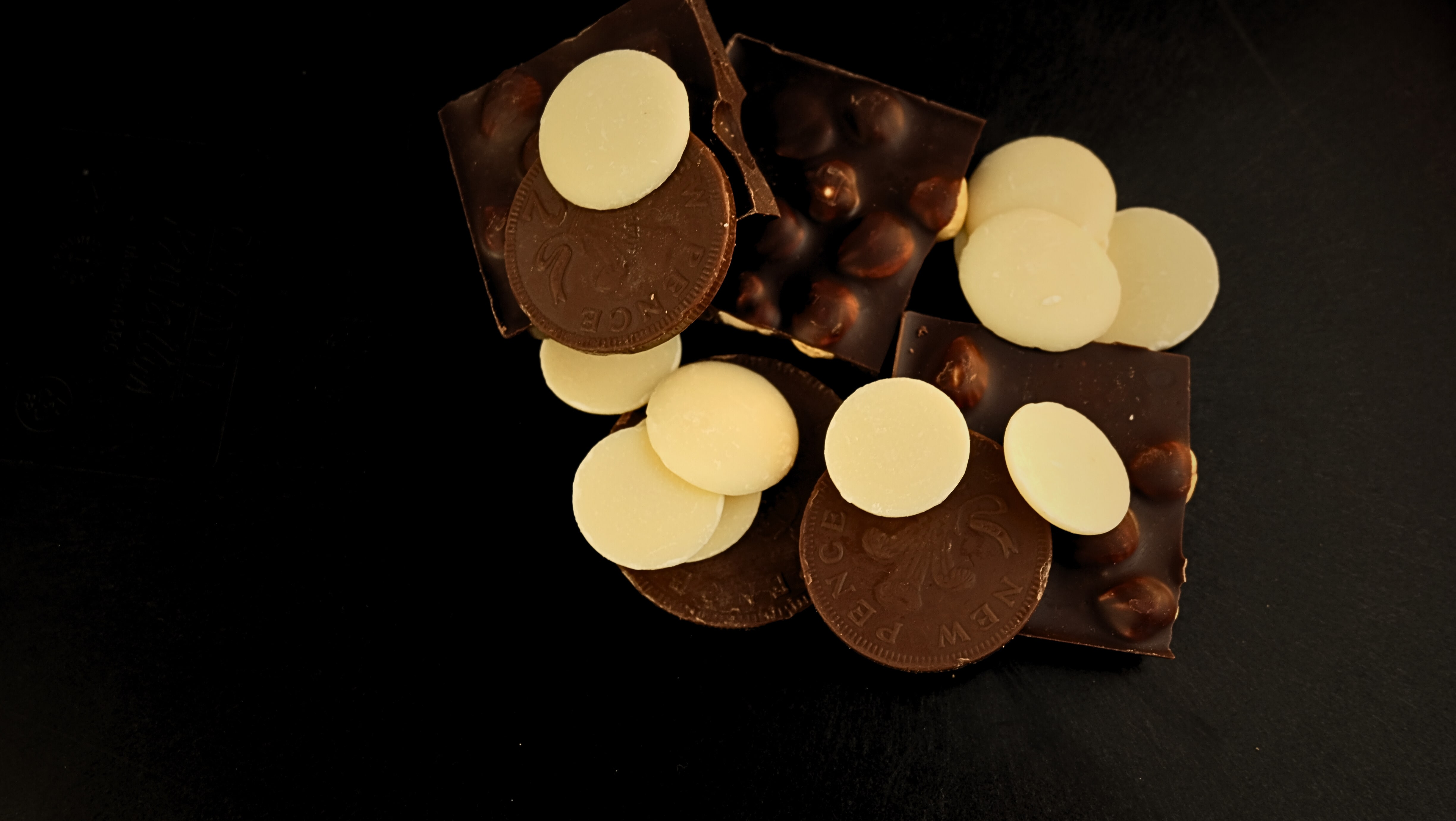 An assortment of milk, white, and dark chocolate products on a black background.