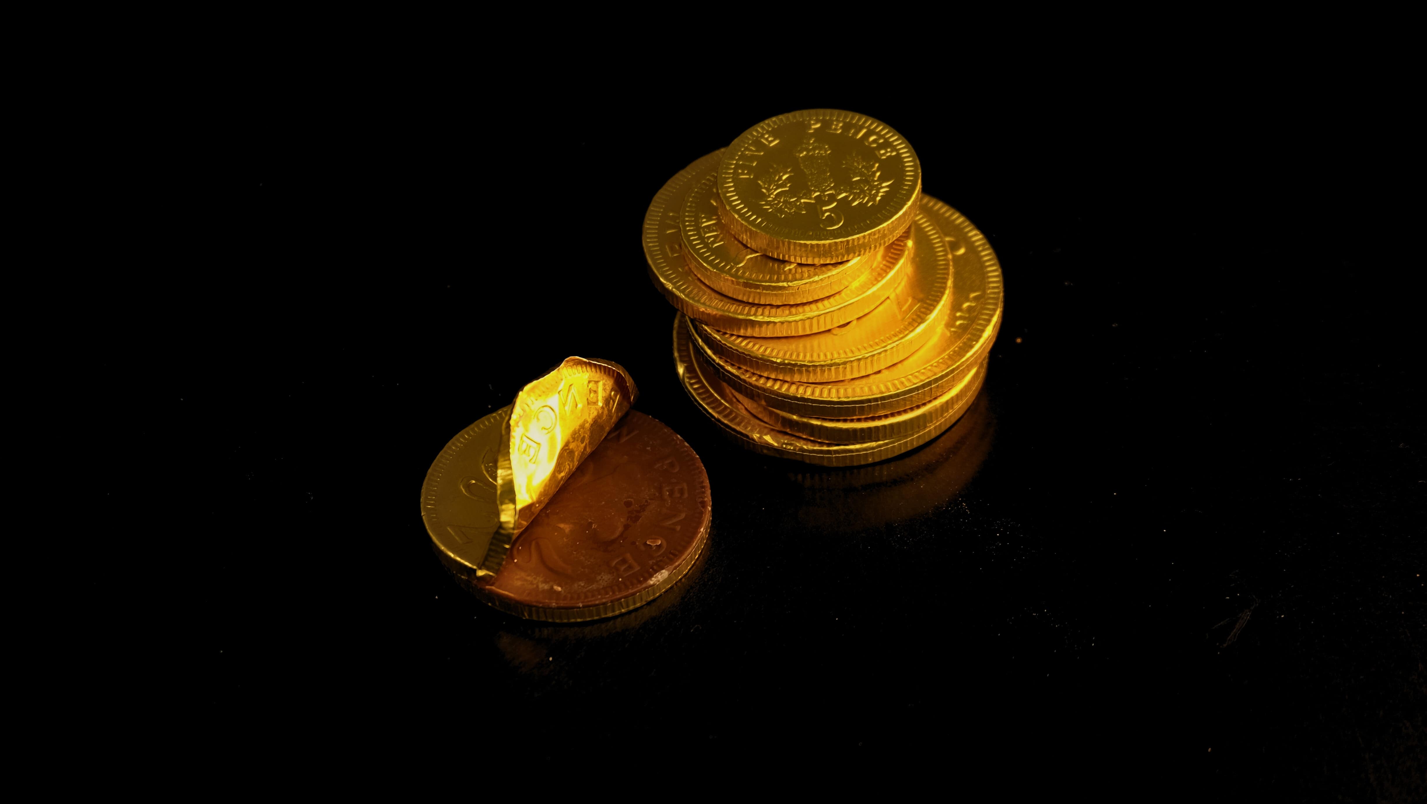 An assortment of novelty festive chocolate coins wrapped in gold foil on a dark surface.