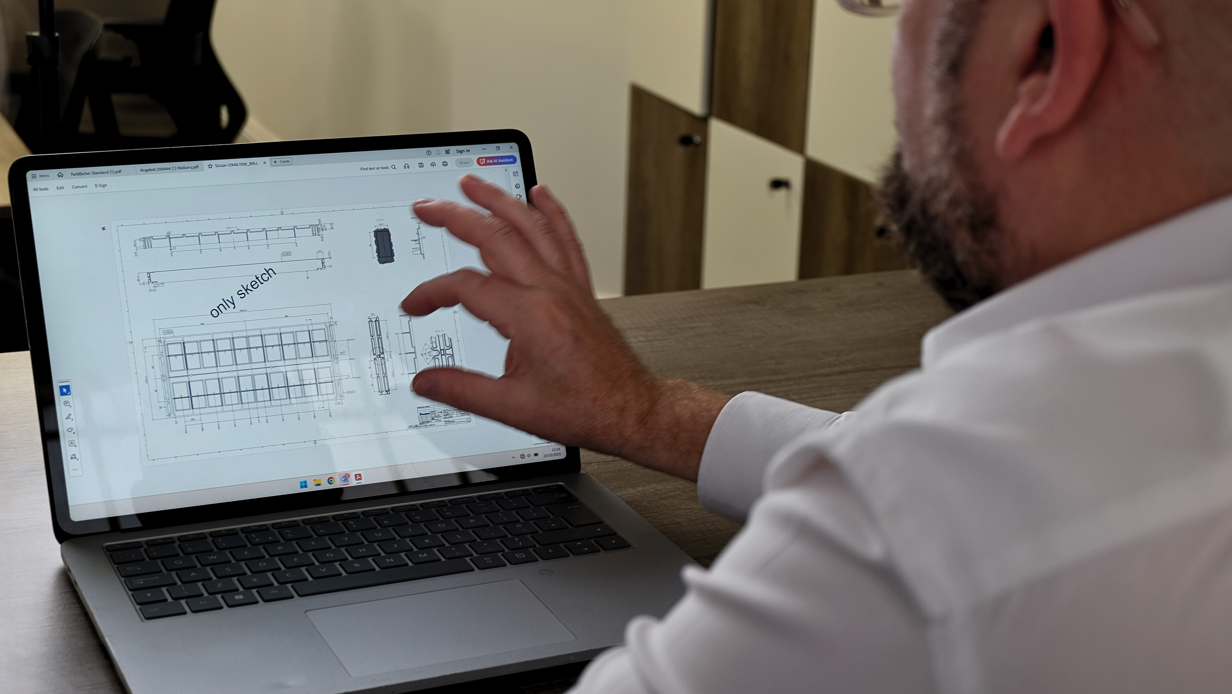 Man studying production machinery sketches on a laptop in an office setting.