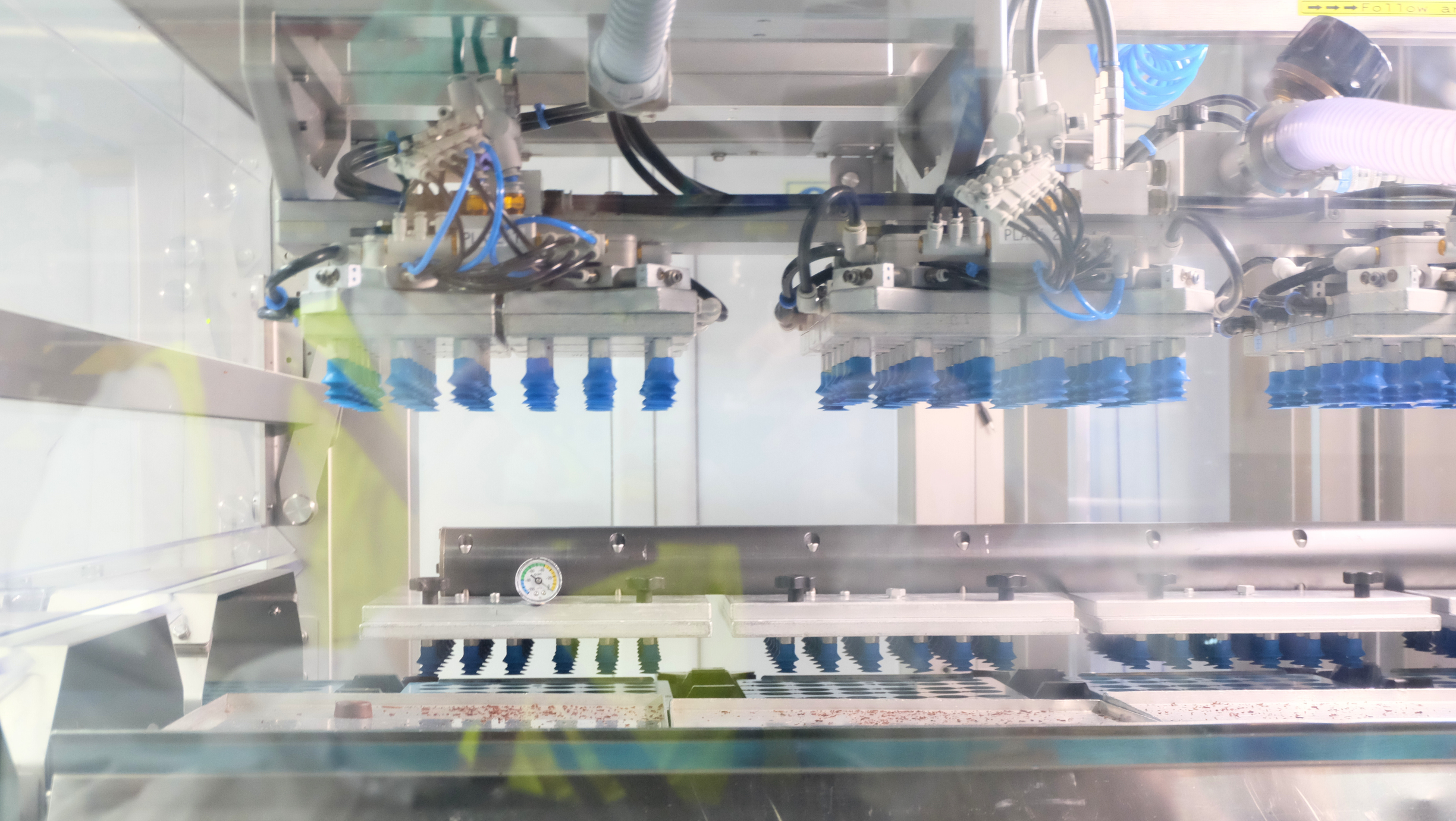 Automated demoulding system with multiple blue suction heads lifting products from moulds.