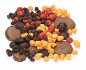 Assorted chocolate and confectionery drops in various sizes and colours, scattered.