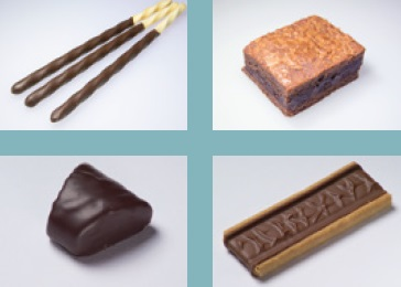 Assorted extruded chocolate products including a brownie, filled bar, and coated piece.