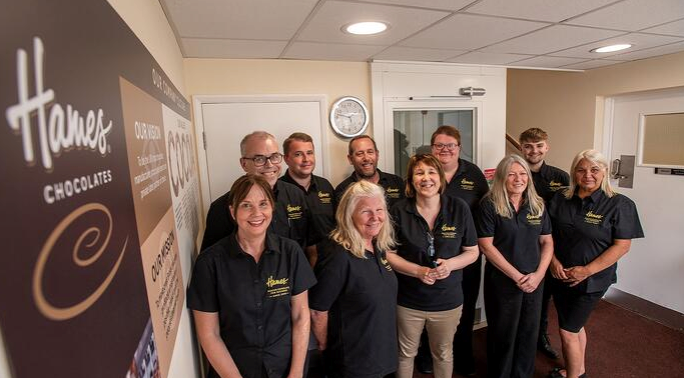 Group of Hames Chocolates staff members smiling in branded uniforms. 