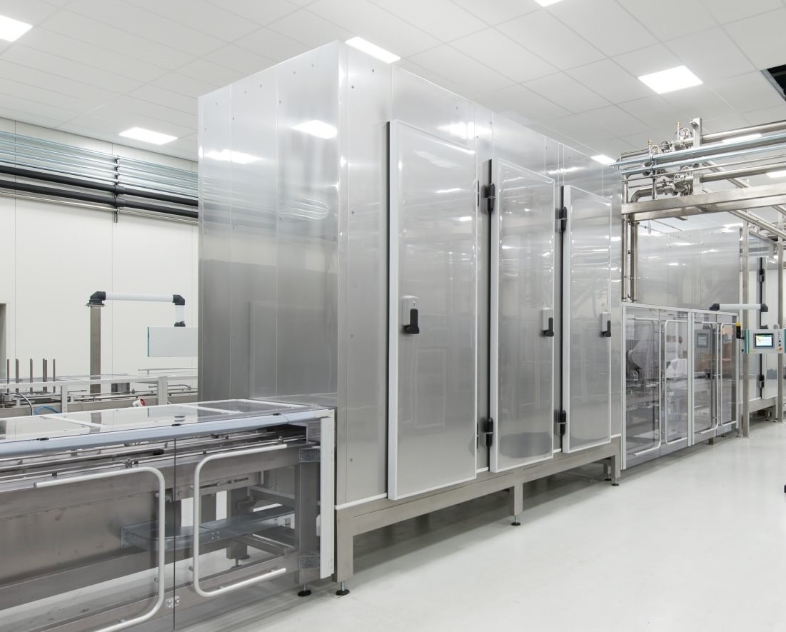 Large enclosed industrial heating unit with conveyor system in a production facility.