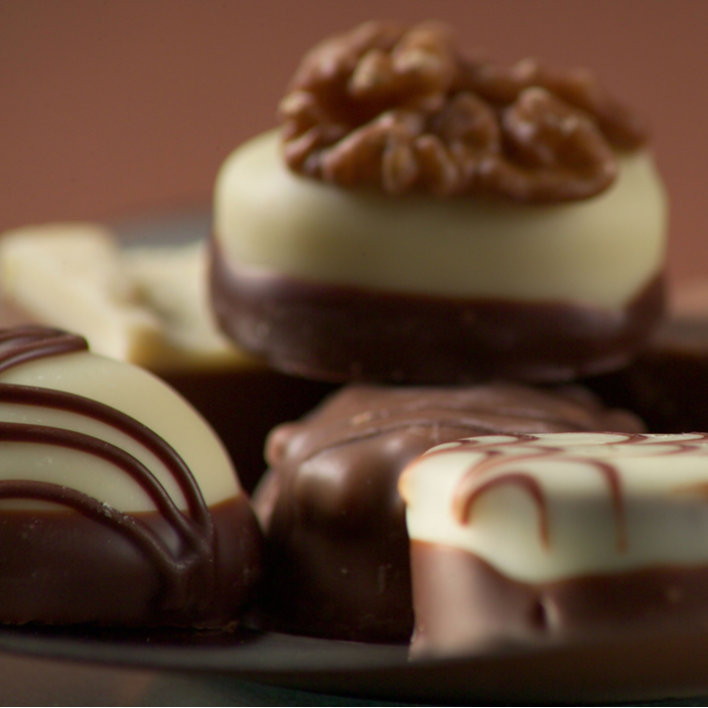 Assorted chocolate pralines with white and milk chocolate layers, one topped with a walnut.