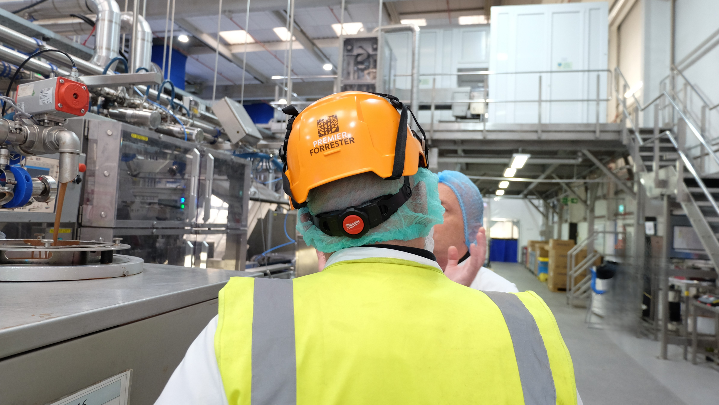 Mike Gee speaking to factory worker in factory setting.