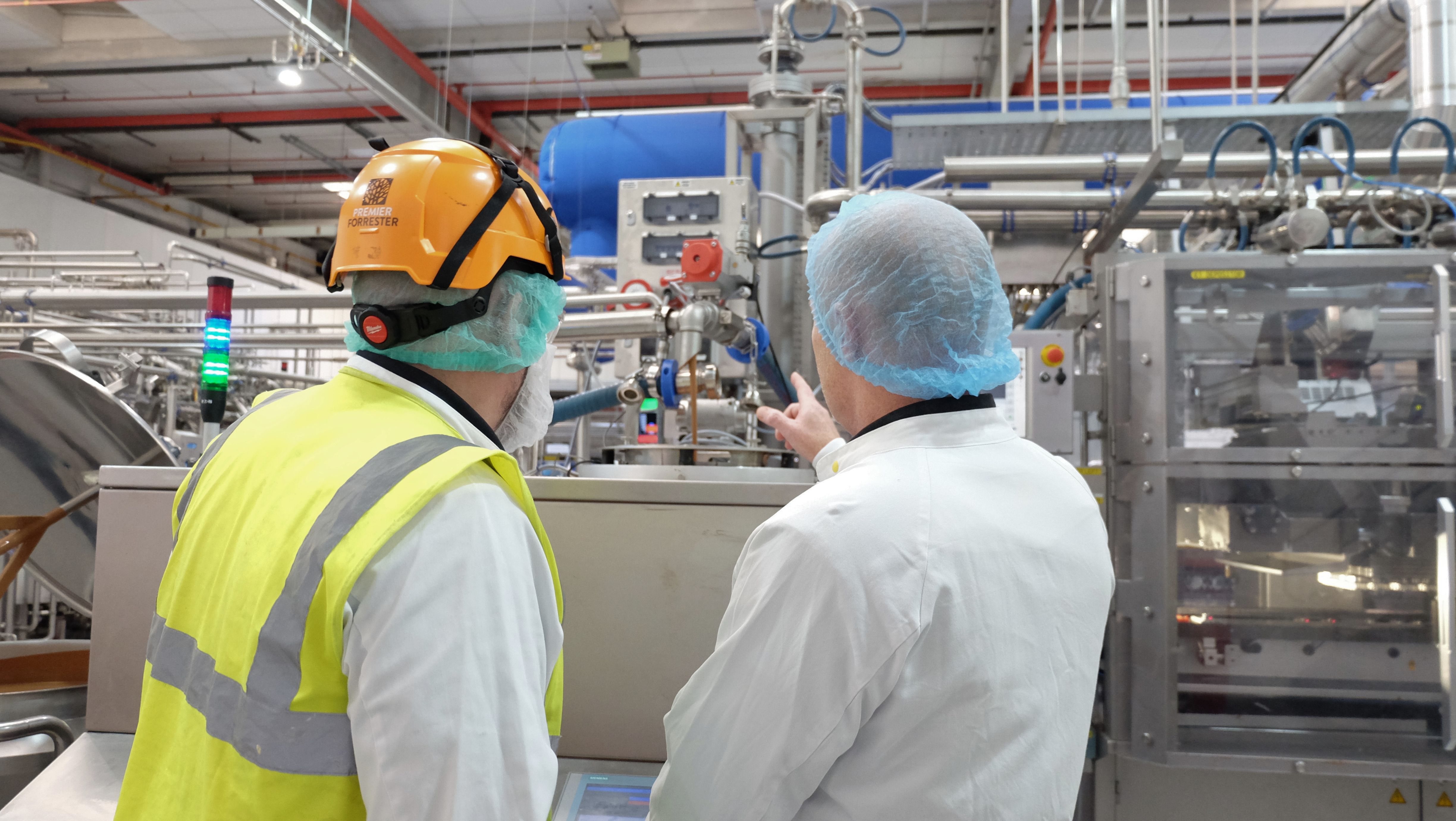 Mike Gee speaking to factory worker in factory setting. 