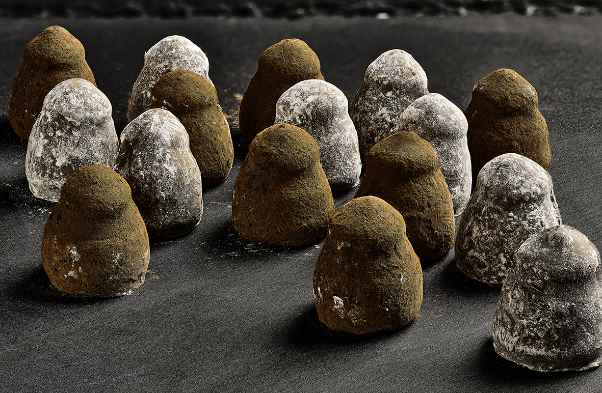 An assortment of chocolate truffles dusted with milk and white toppings.