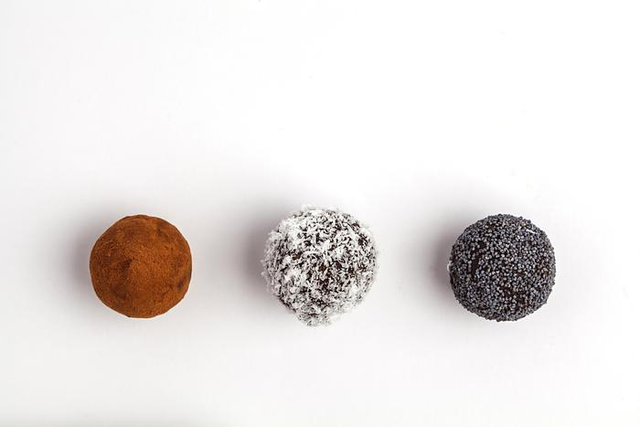 Three chocolate truffles coated in cocoa powder, shredded coconut, and chocolate sprinkles.
