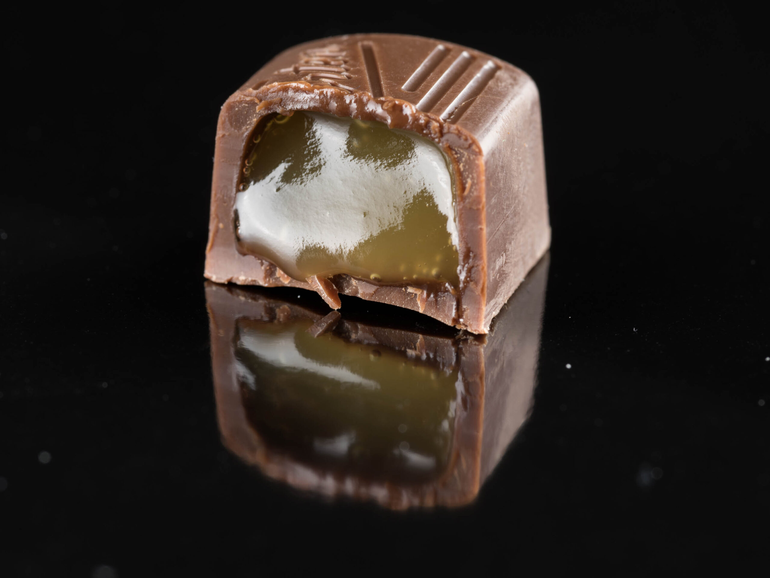 A filled chocolate cut in half to show a gooey caramel centre.