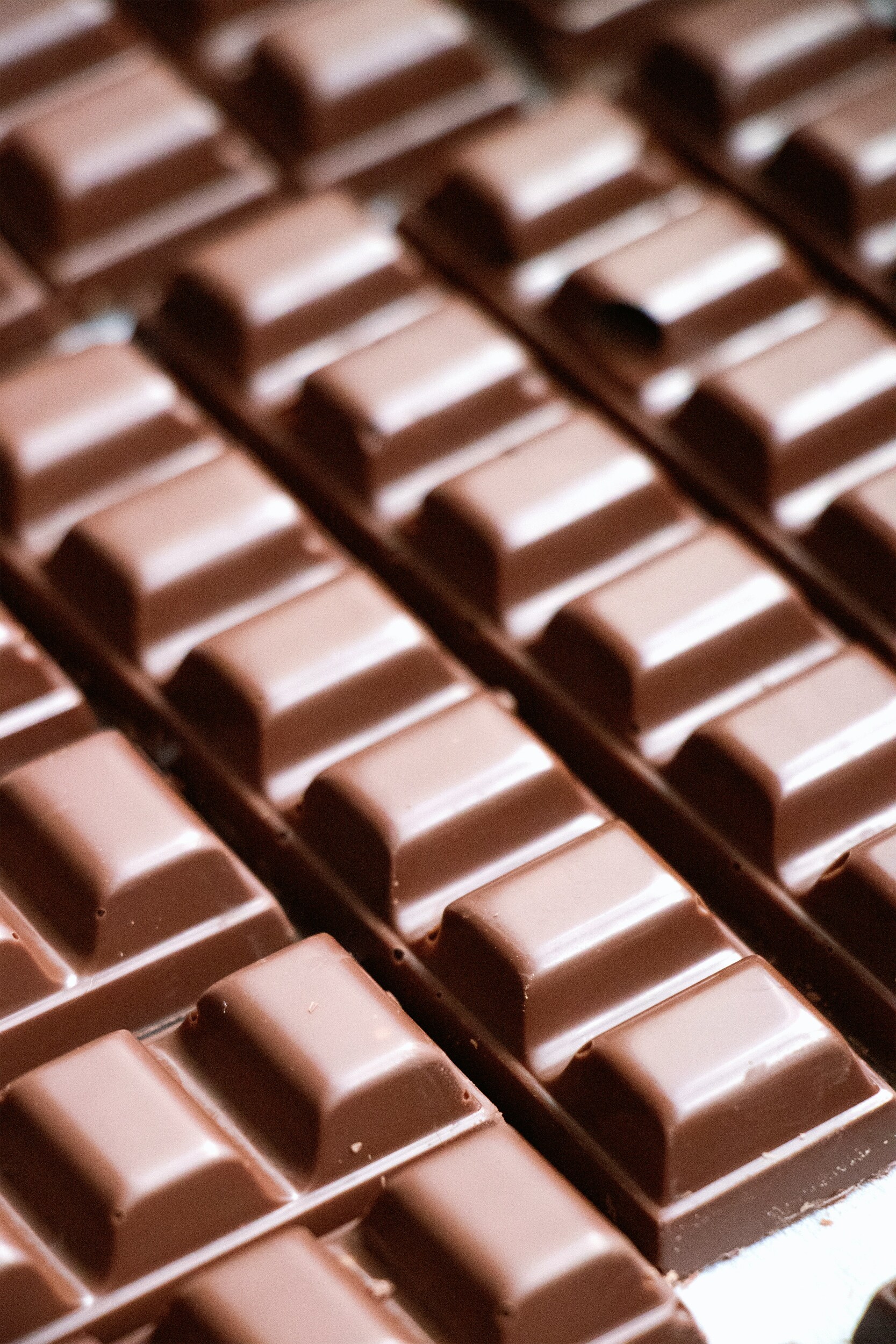 Close-up of milk chocolate bars arranged in rows, showing a smooth segmented surface.