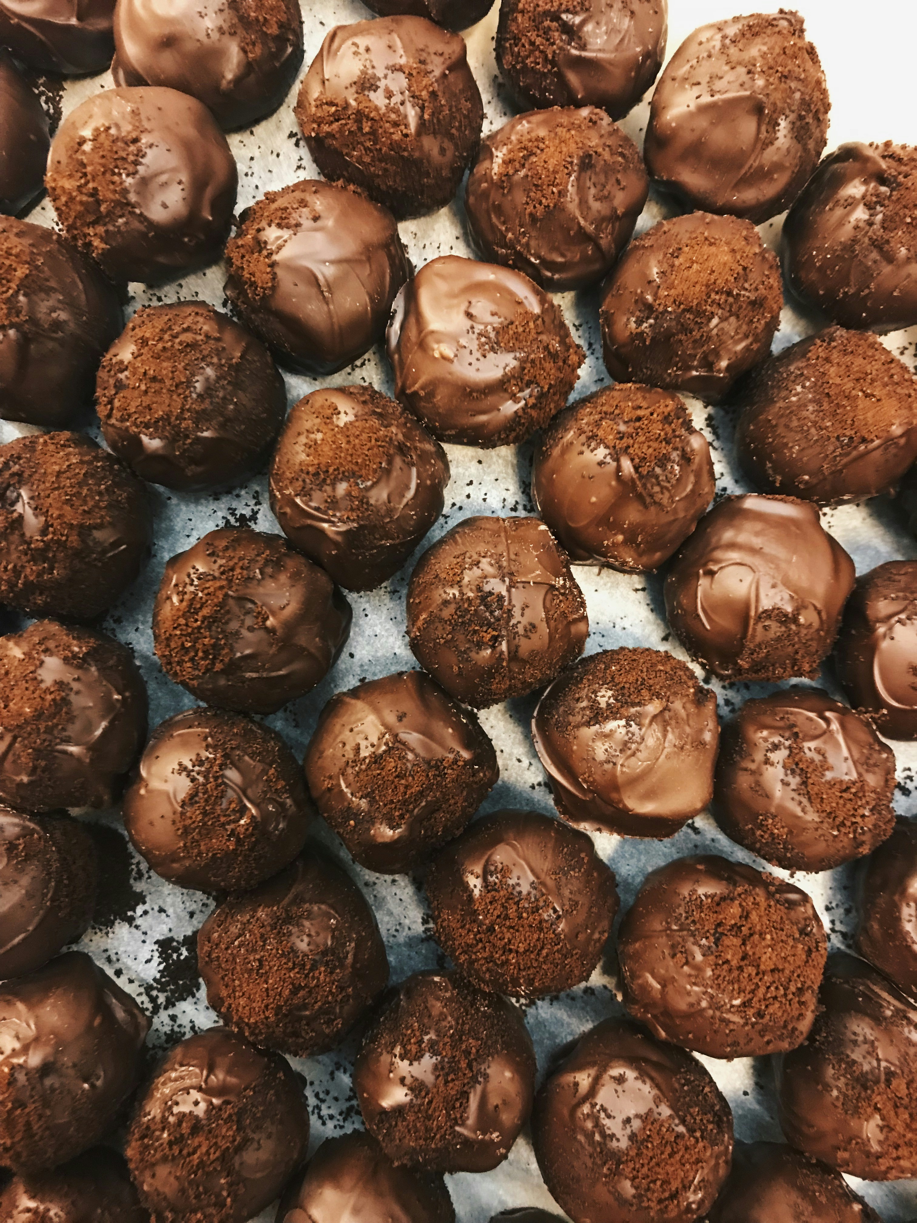 Tray of chocolate truffles coated in milk chocolate with a dusting of chocolate topping.