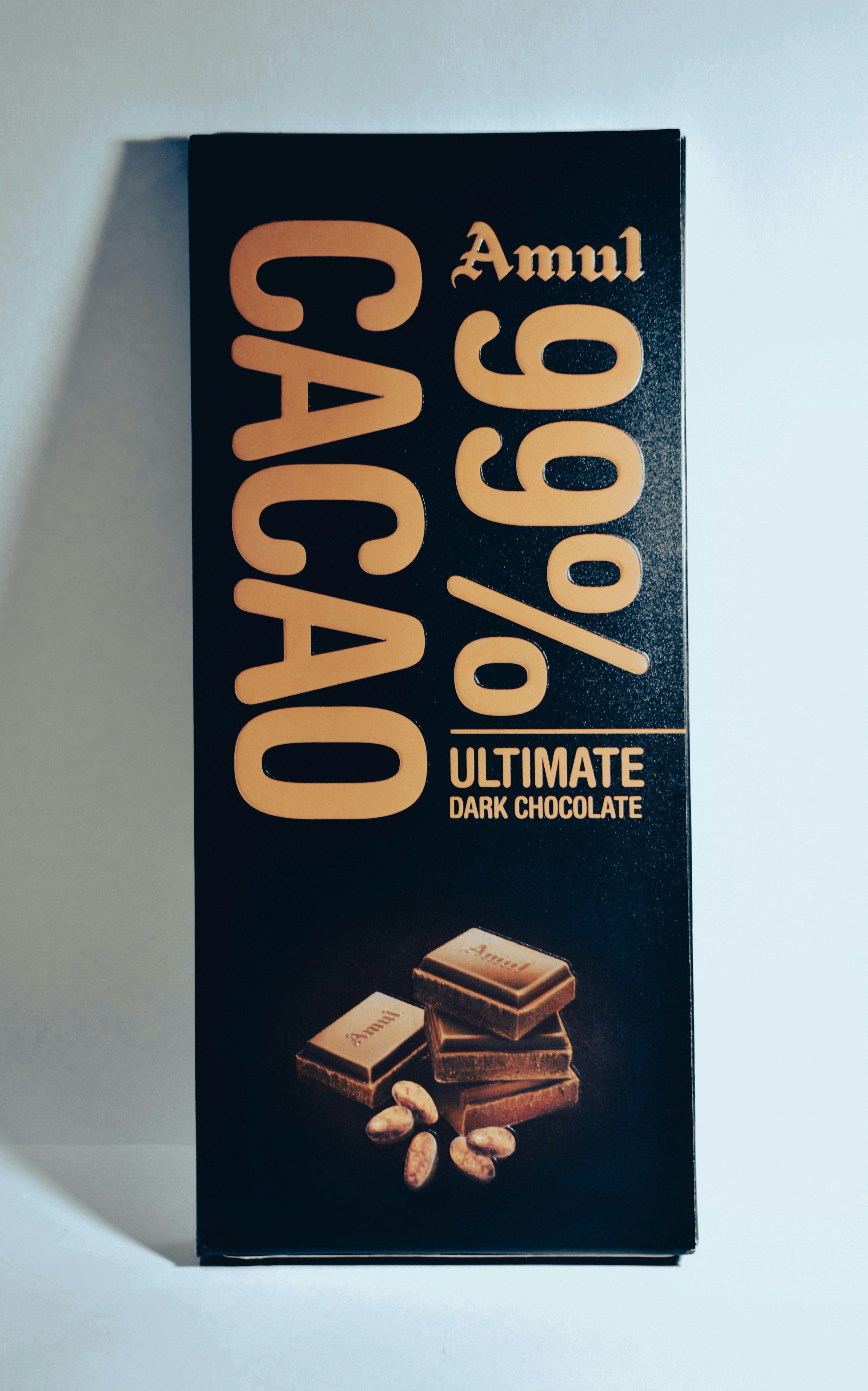 A bar of 99% dark chocolate wrapped in paper packaging on a white surface.