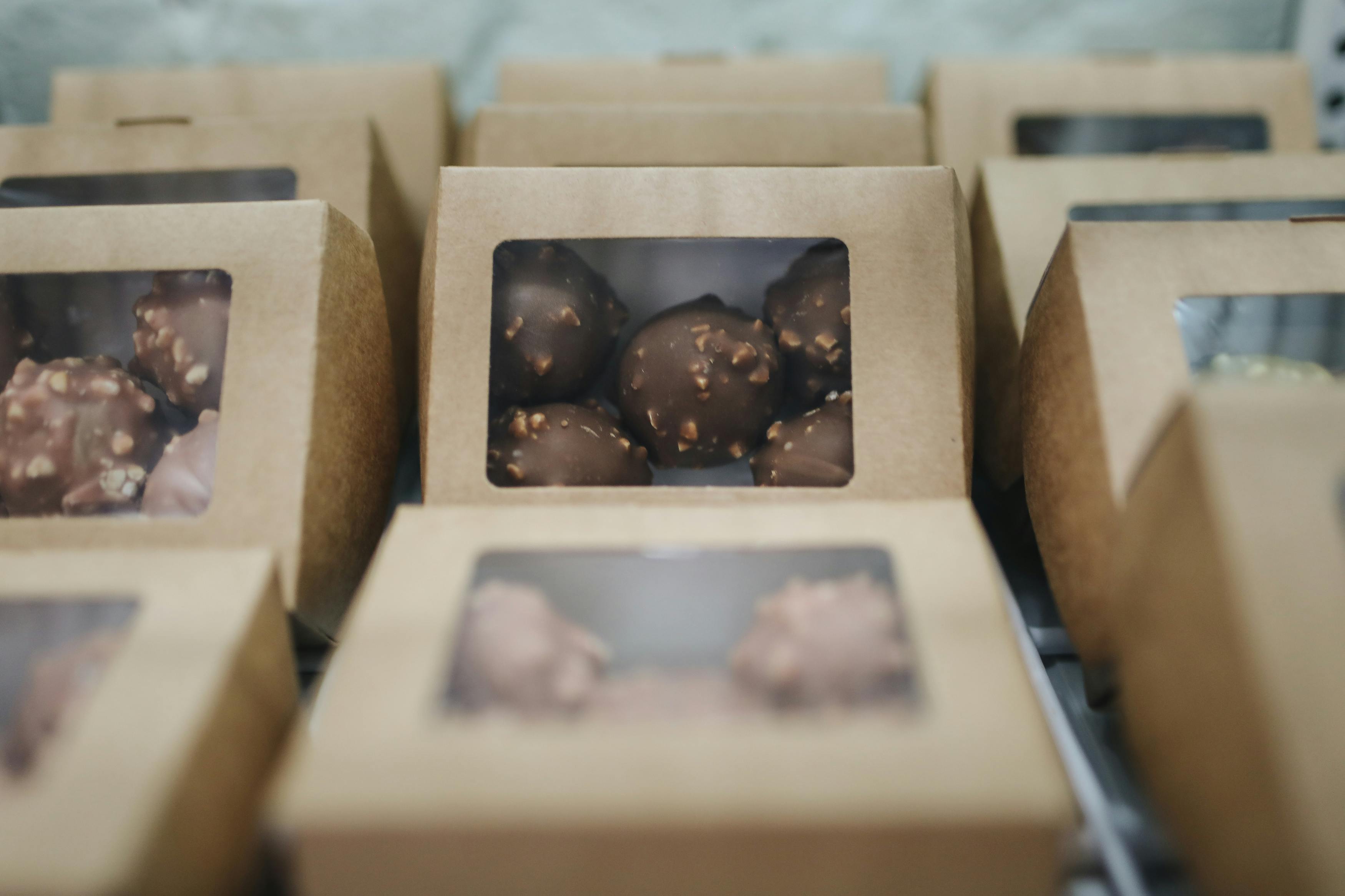 Chocolate truffles packaged in eco-friendly cardboard boxes arranged in rows.