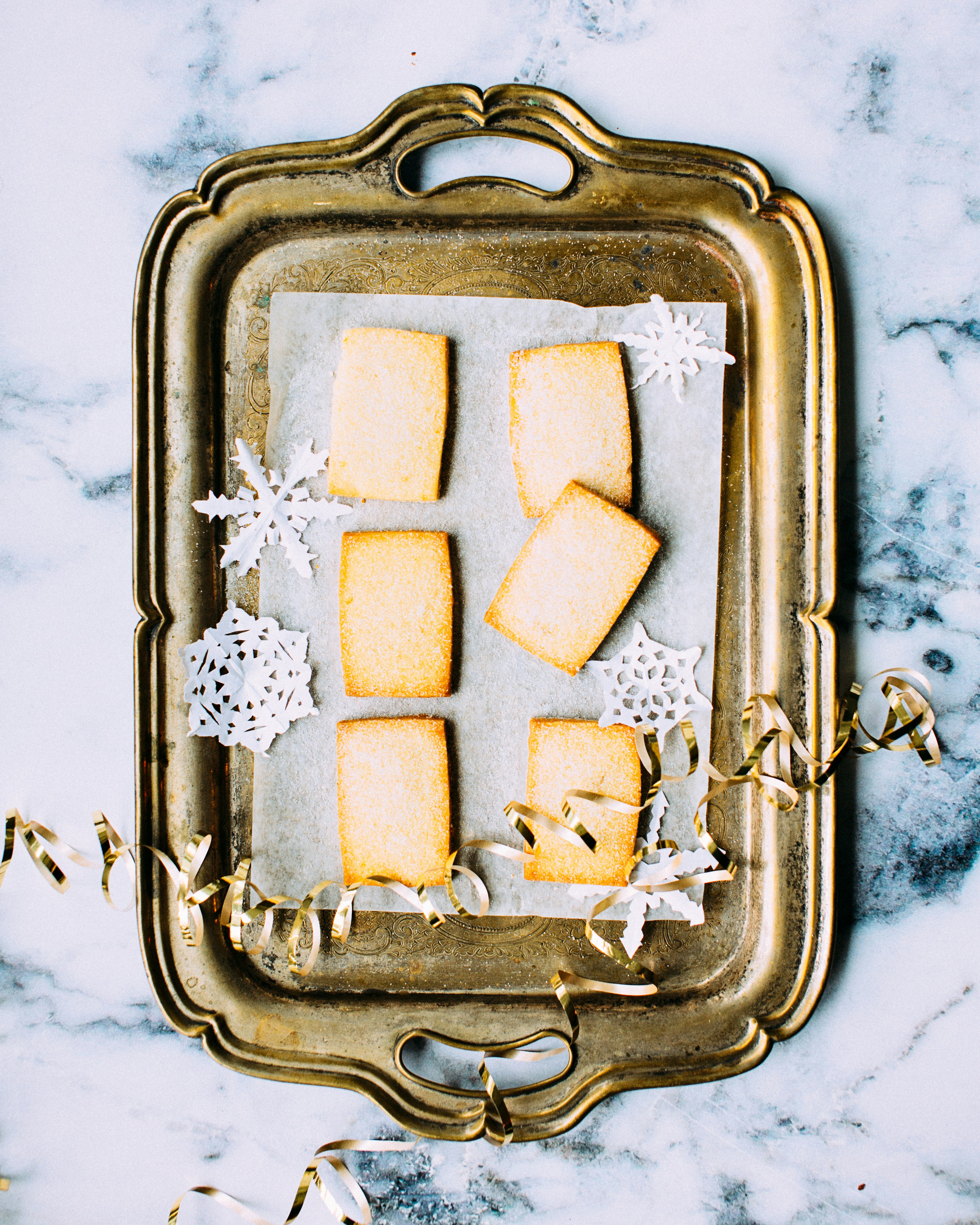 Homemade rectangle biscuits on a silver tray with scattered festive decorations.