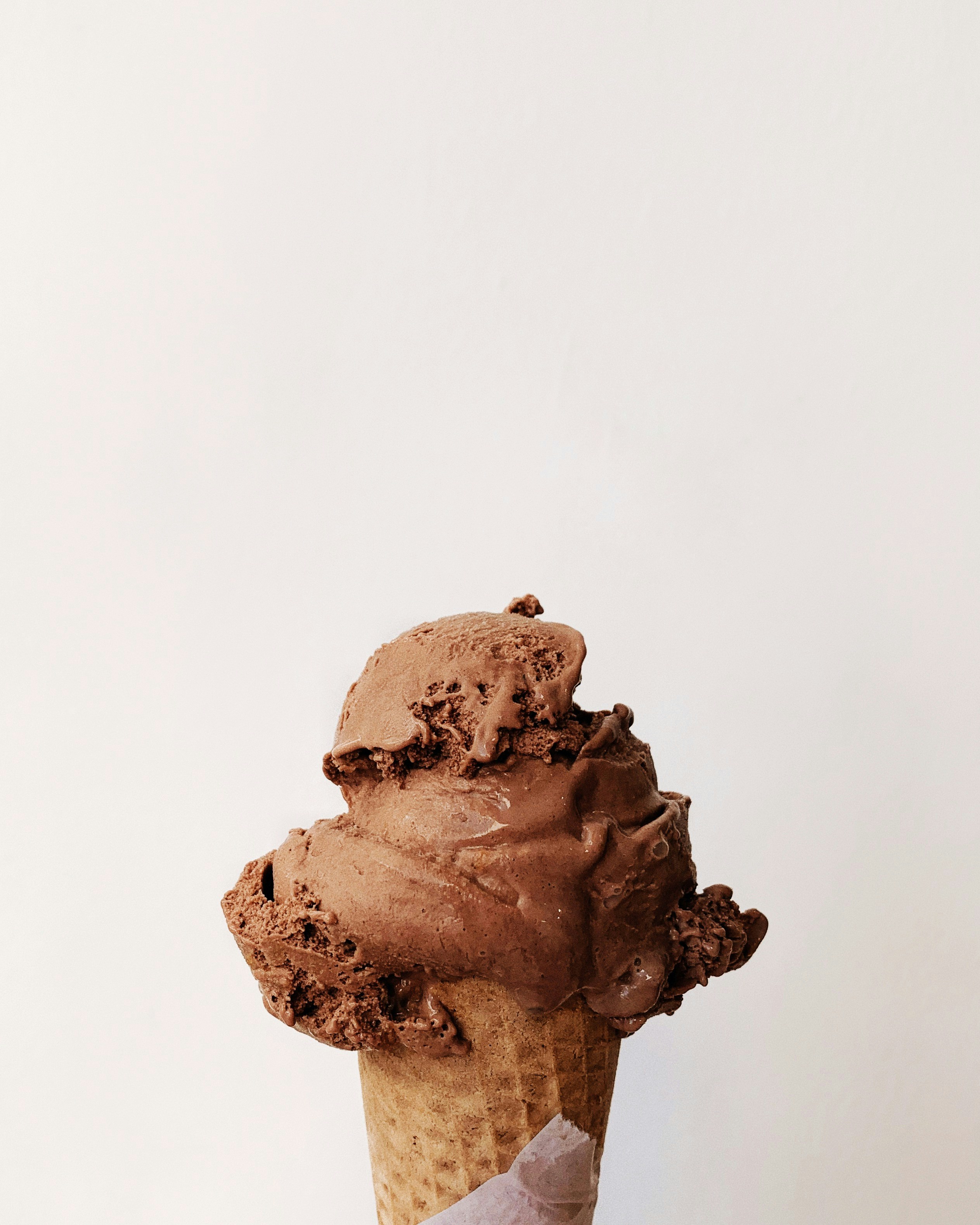 Close-up of a cone of chocolate gelato against a light background.