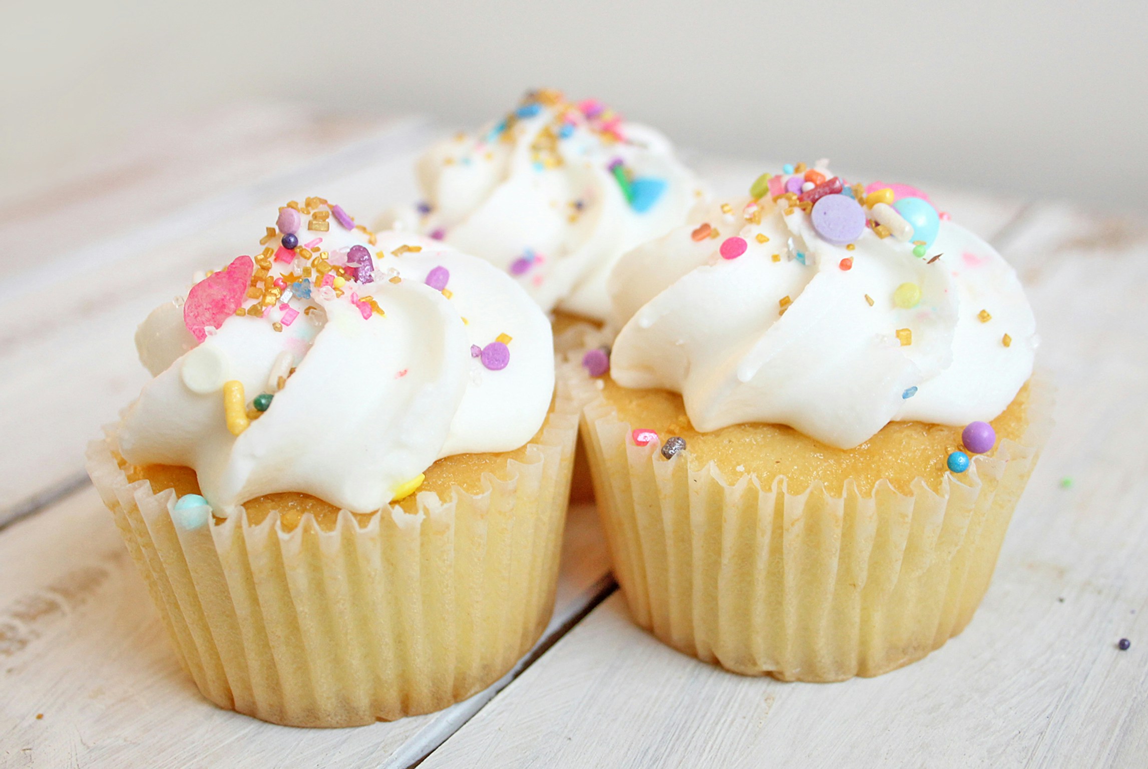 vanilla cupcakes with cream and sprinkles on top.
