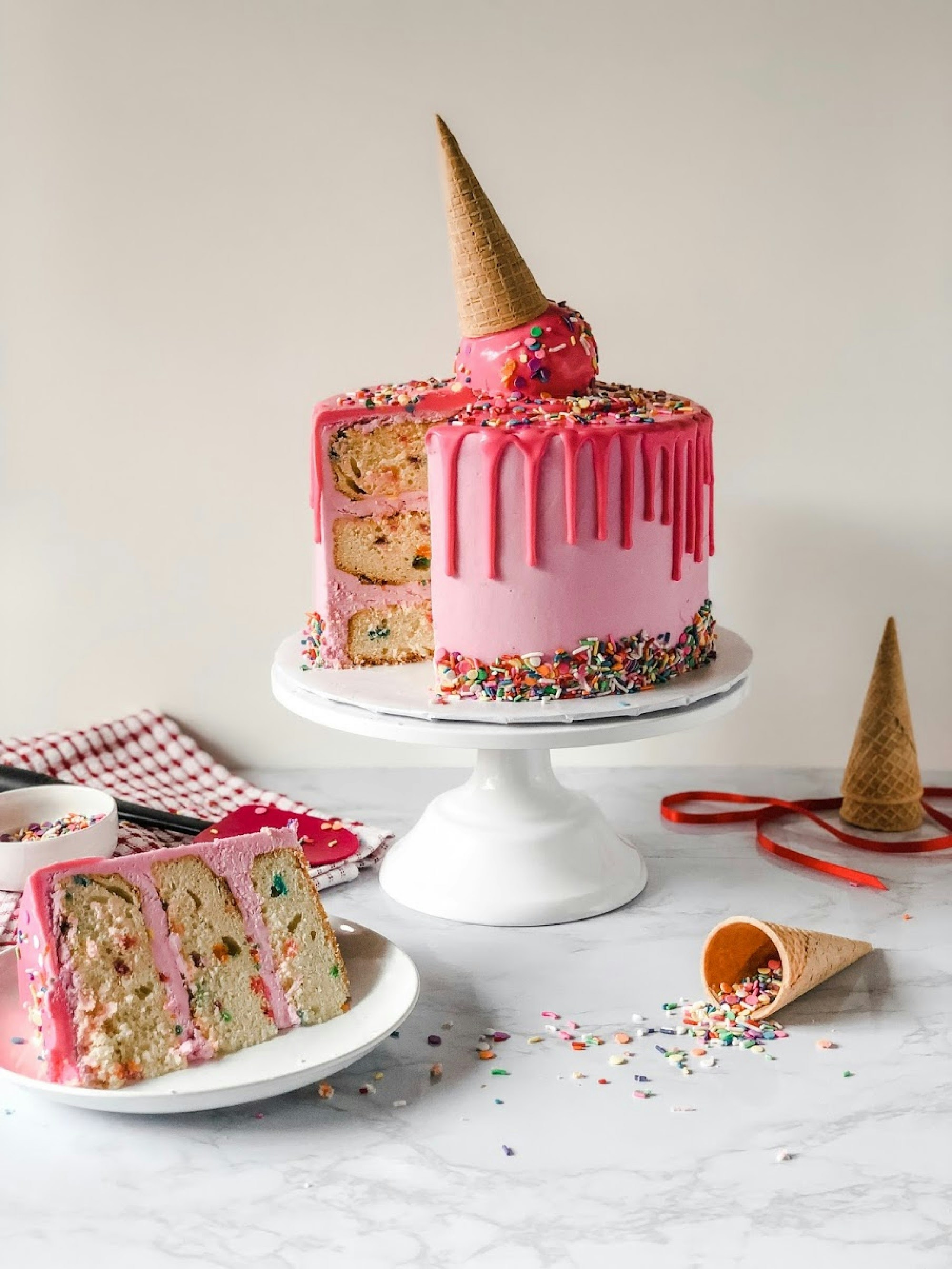 colourful pink cake, cut open with ice cream on top.