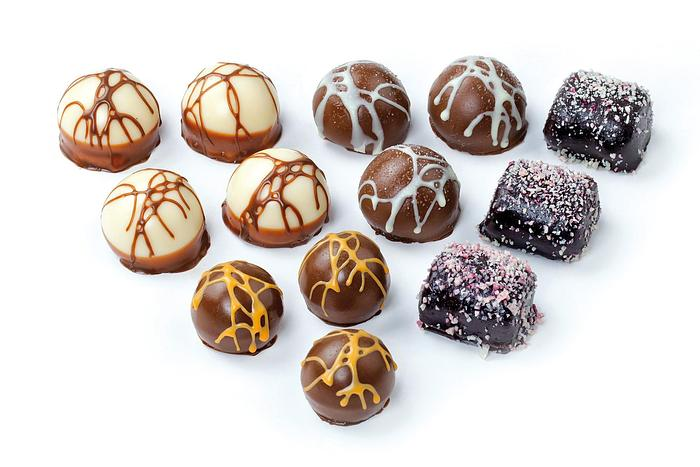 An assortment of milk, white, and dark moulded chocolates decorated with drizzles and sprinkles.
