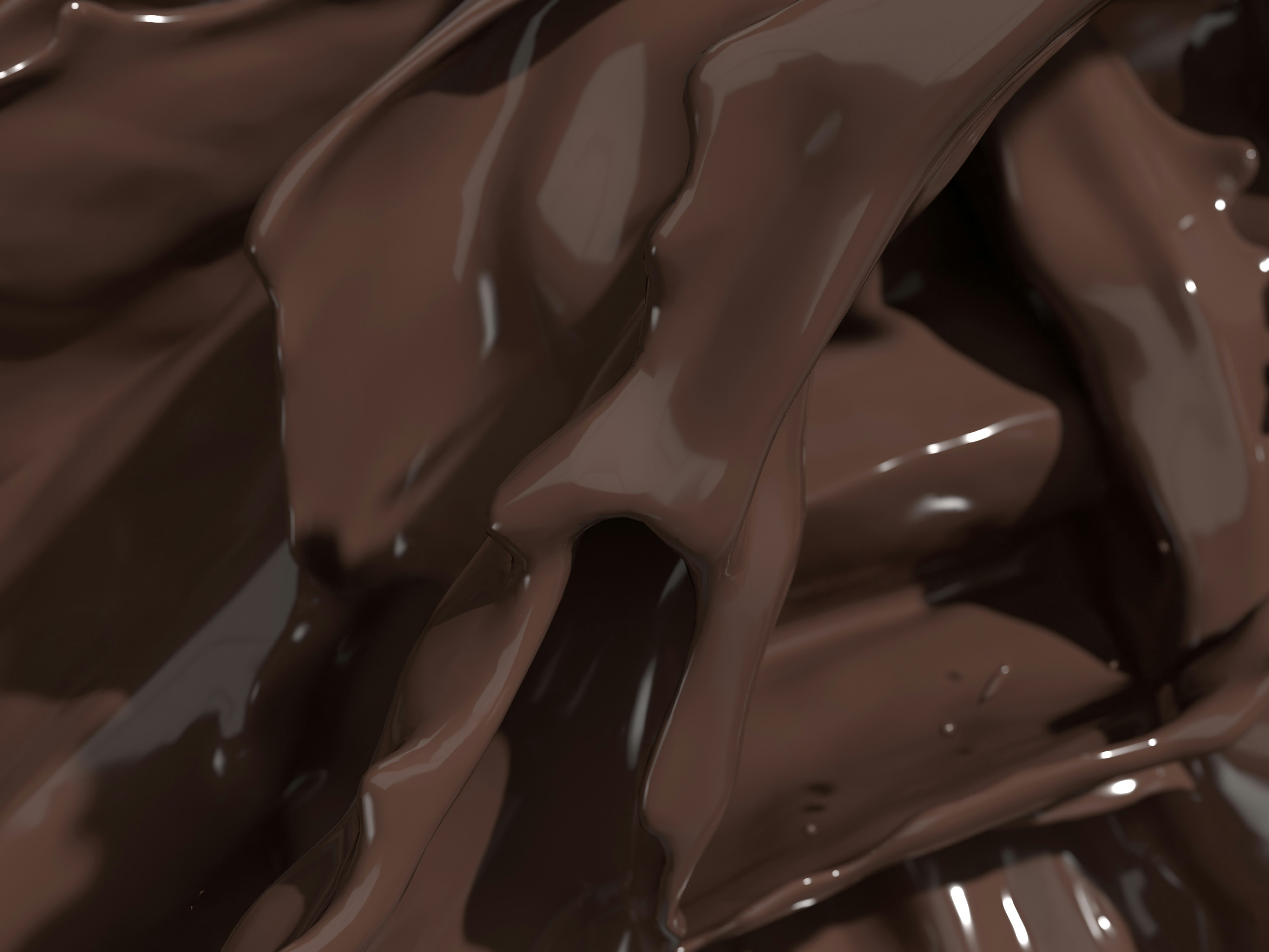 A close-up of dark flowing melted chocolate in liquid form.