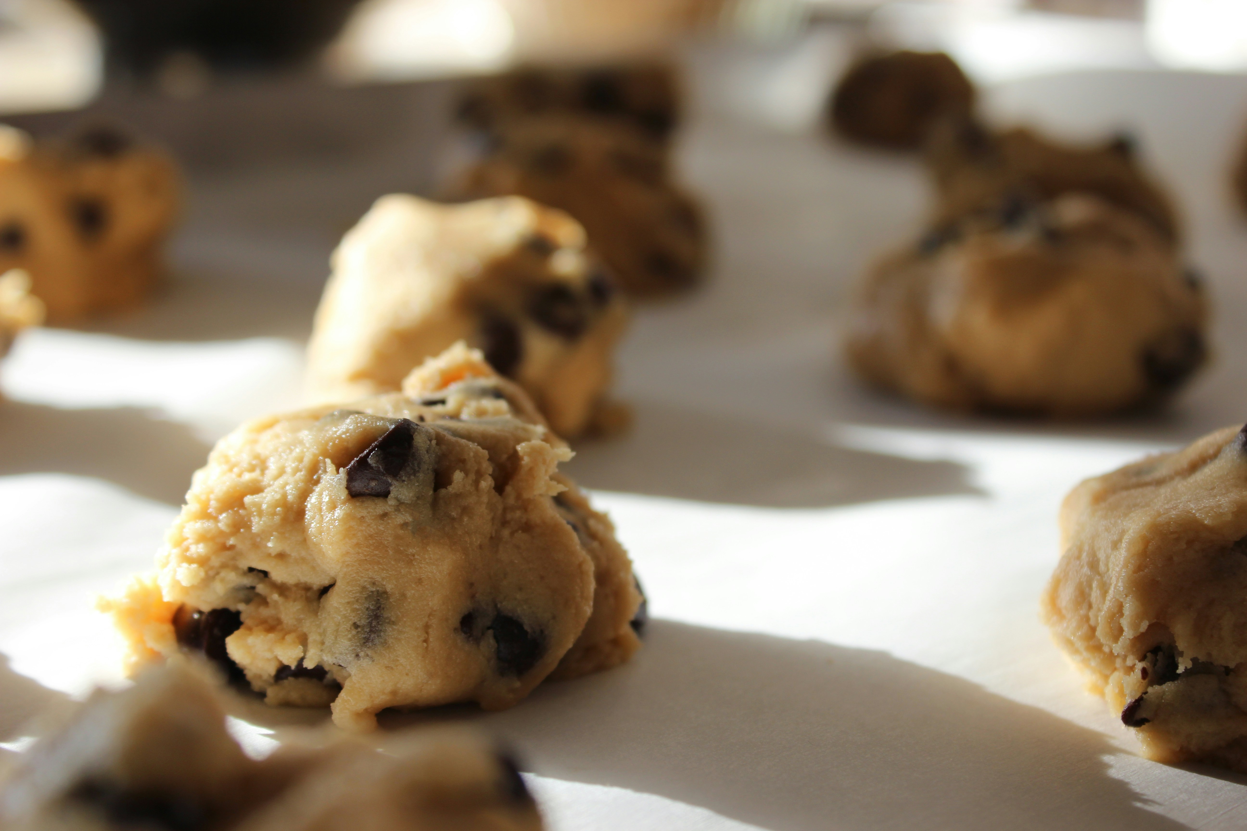 Close up of cookie dough balls laid out on sheet.
