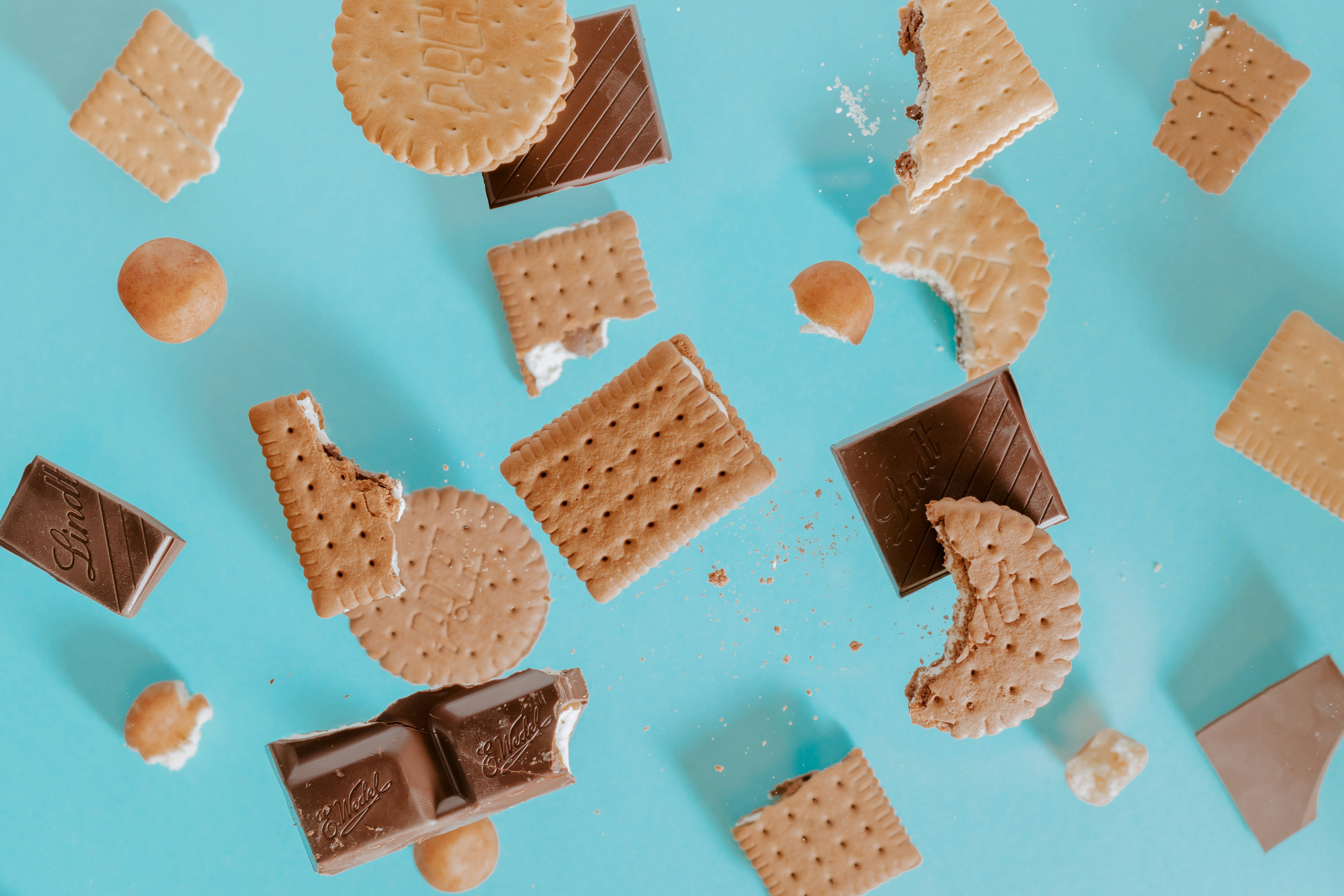 Assortment of cookies, biscuits, and chocolate on blue backdrop.