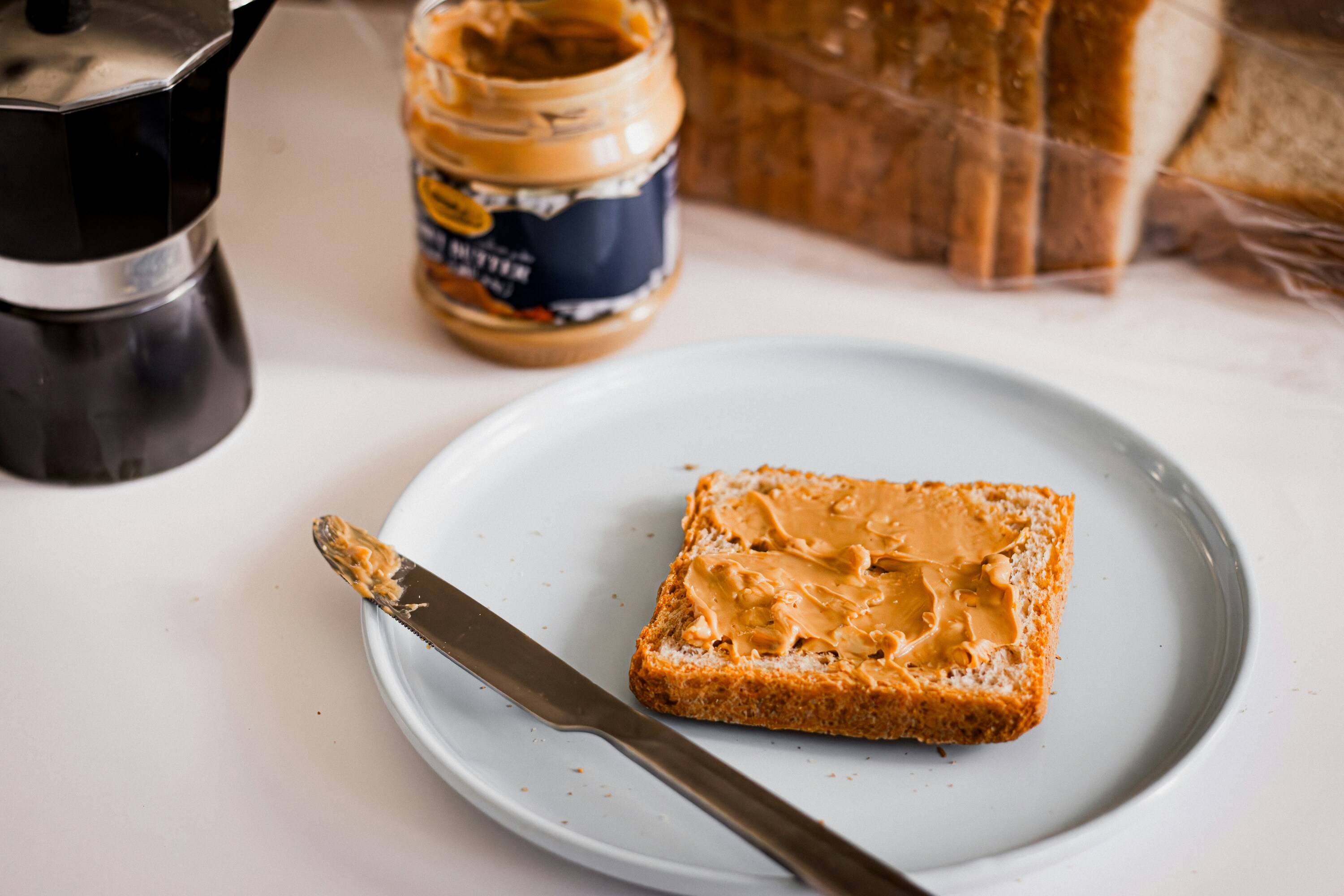 Peanut butter spread on toast, with jar in the background.
