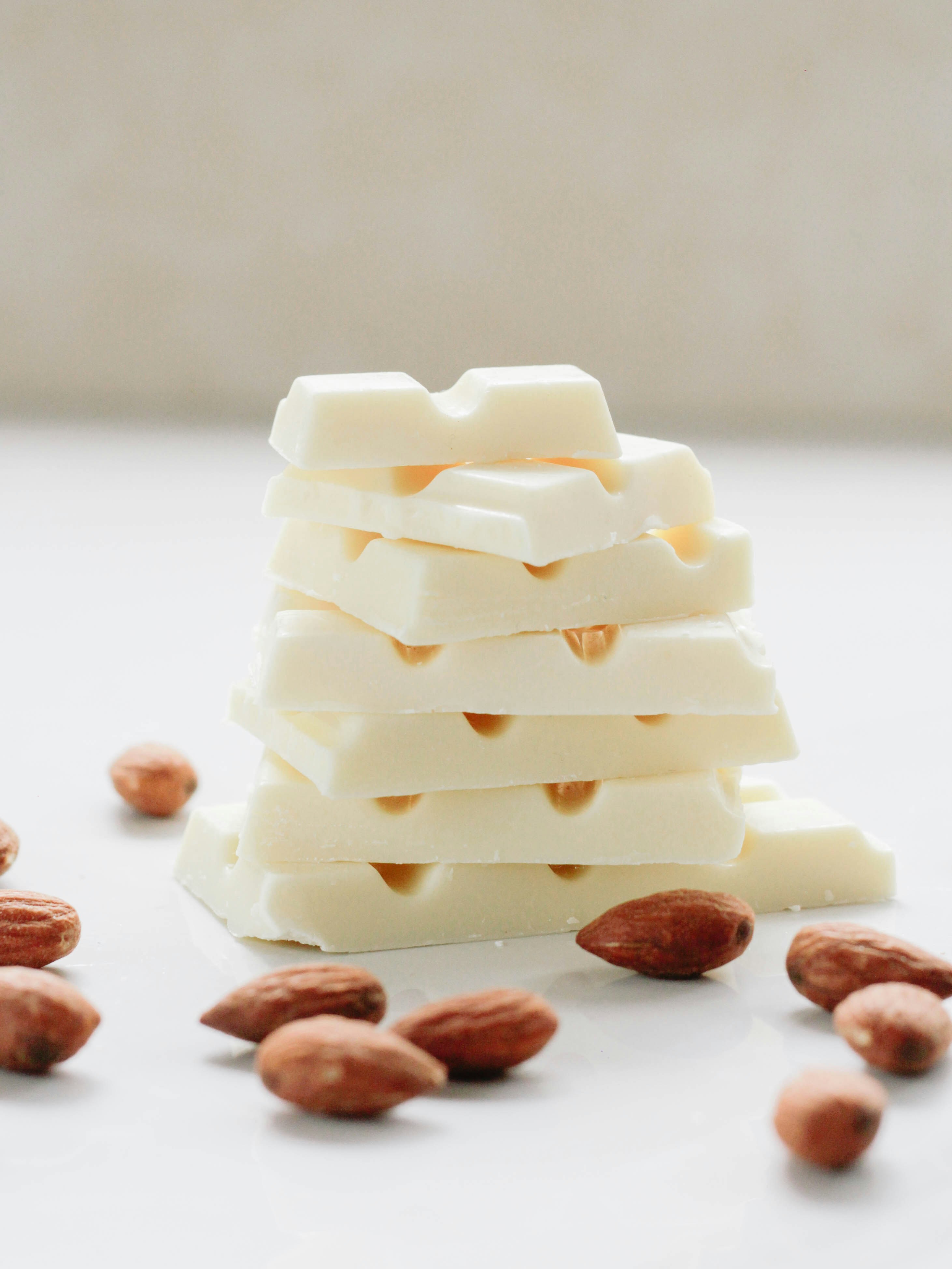 Stacked white chocolate with almonds scattered around.